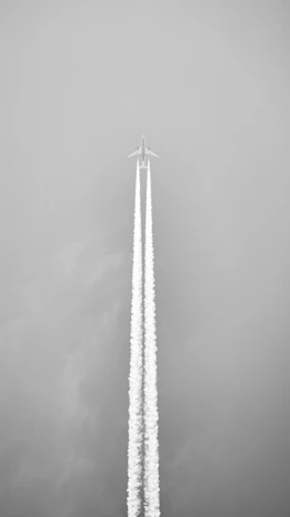 Airplane leaving a contrail against a gray sky