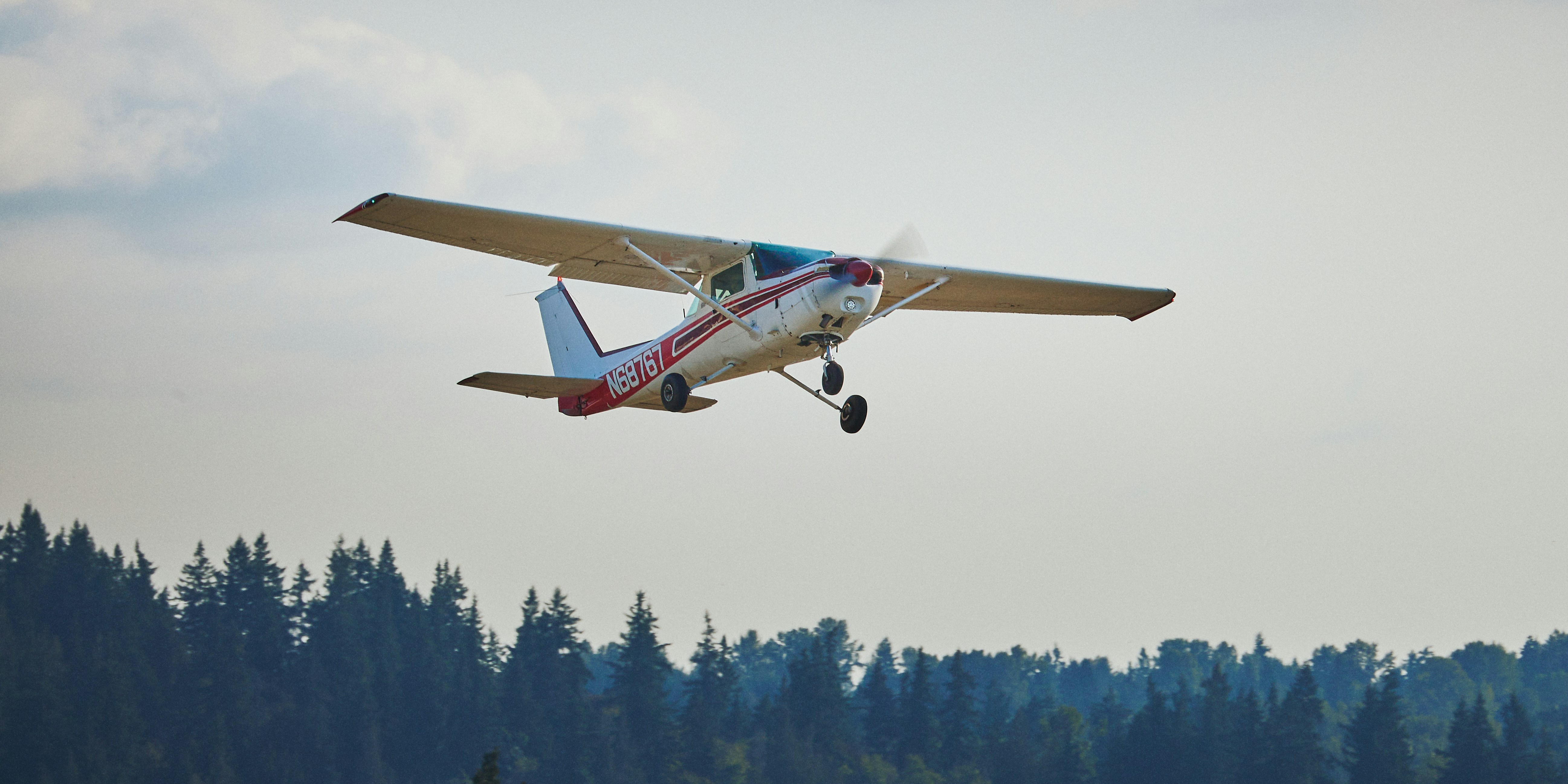 Small airplane flying over a forest
