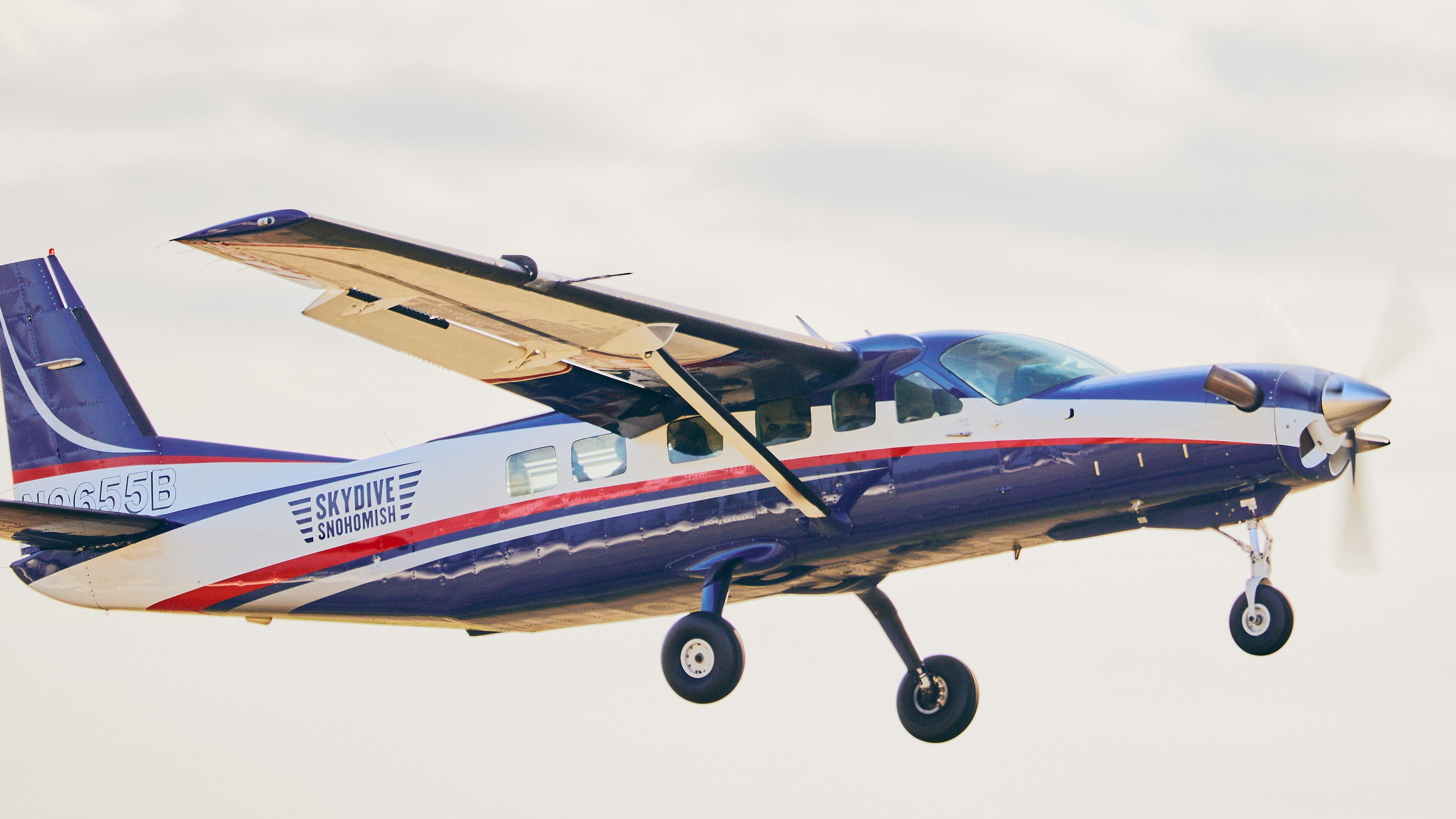 A blue and white propeller plane flying in the sky.