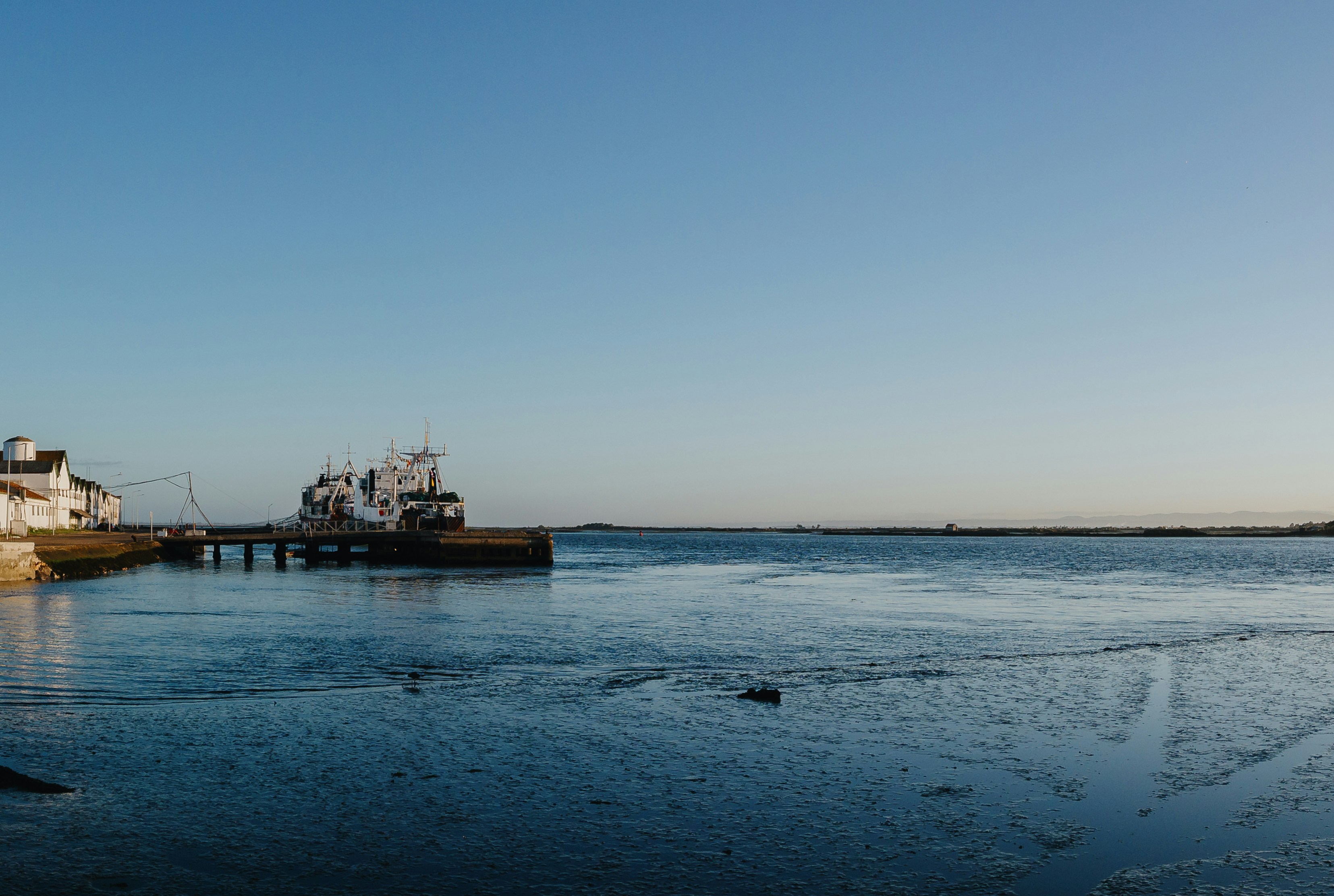 Barche attraccate a un molo su un mare blu calmo.