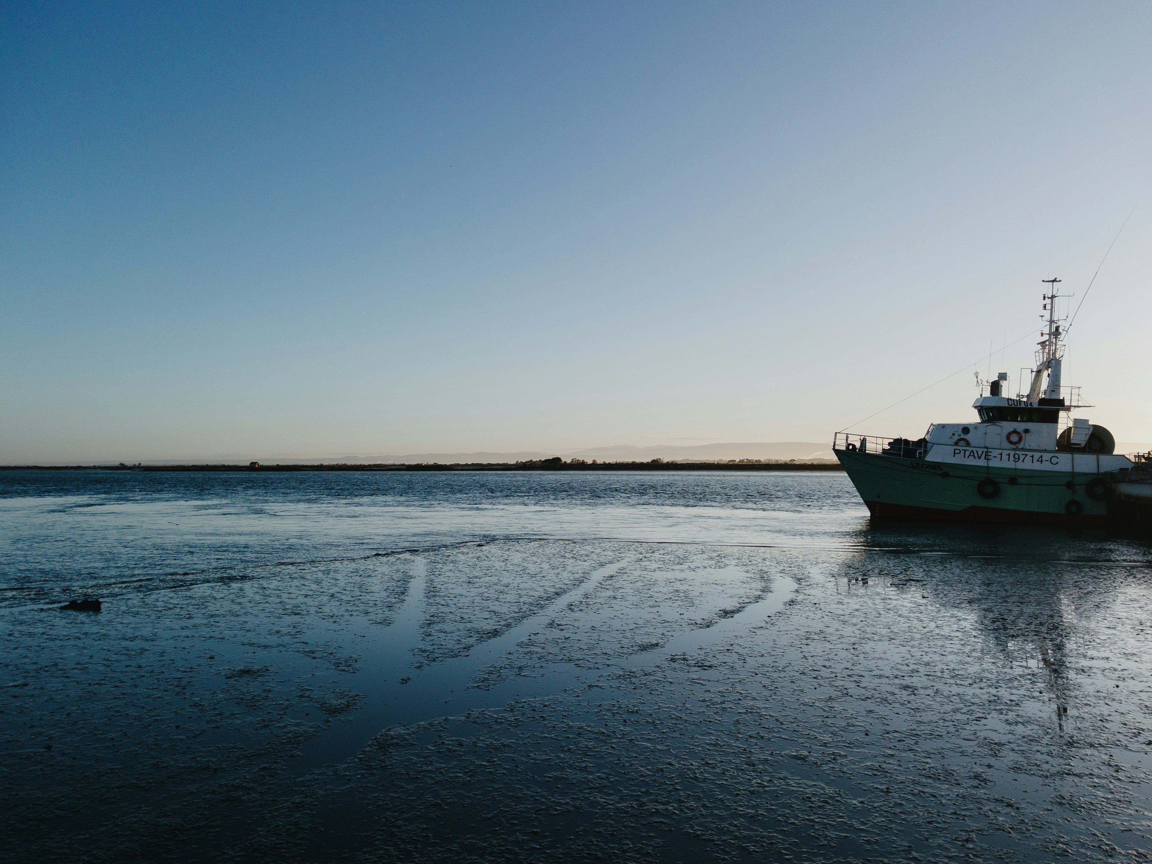 Una barca si riposa vicino all'acqua al tramonto.