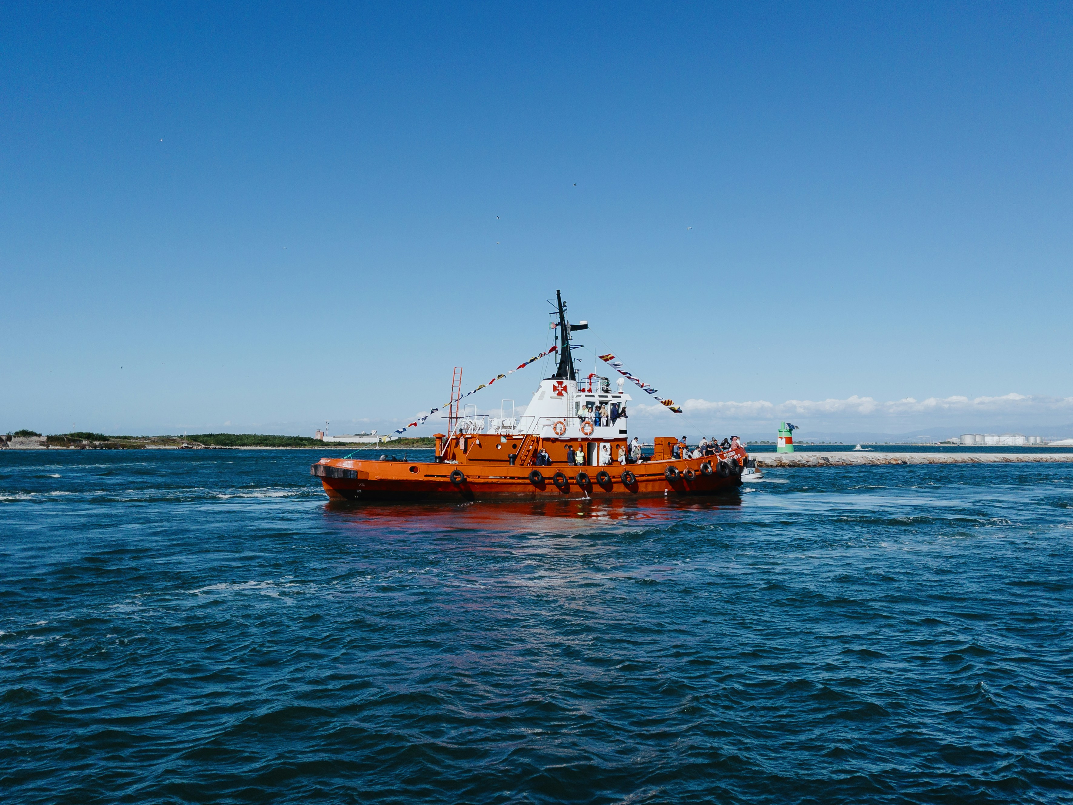 Barca arancione che naviga sull'acqua blu sotto il cielo limpido