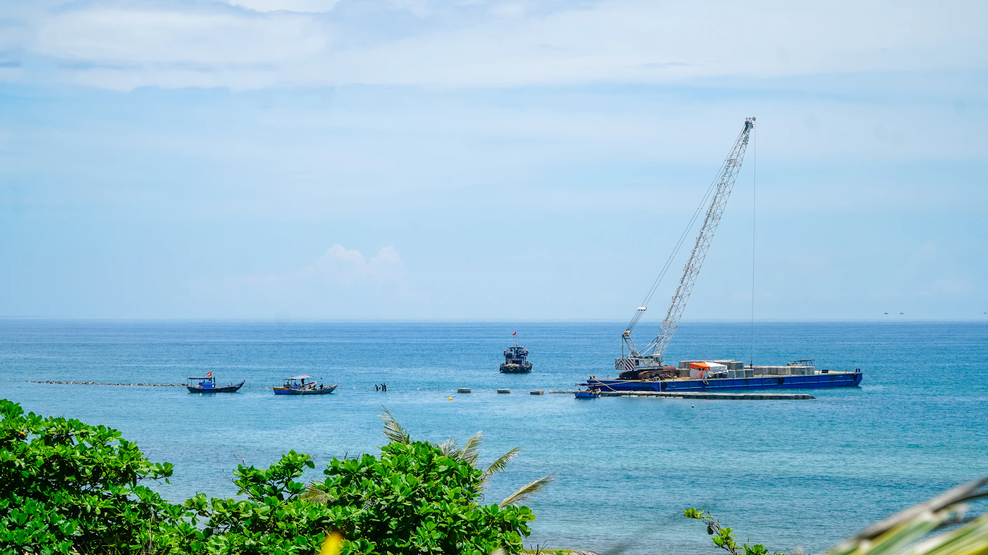Crane barge working on a large vessel at sea.