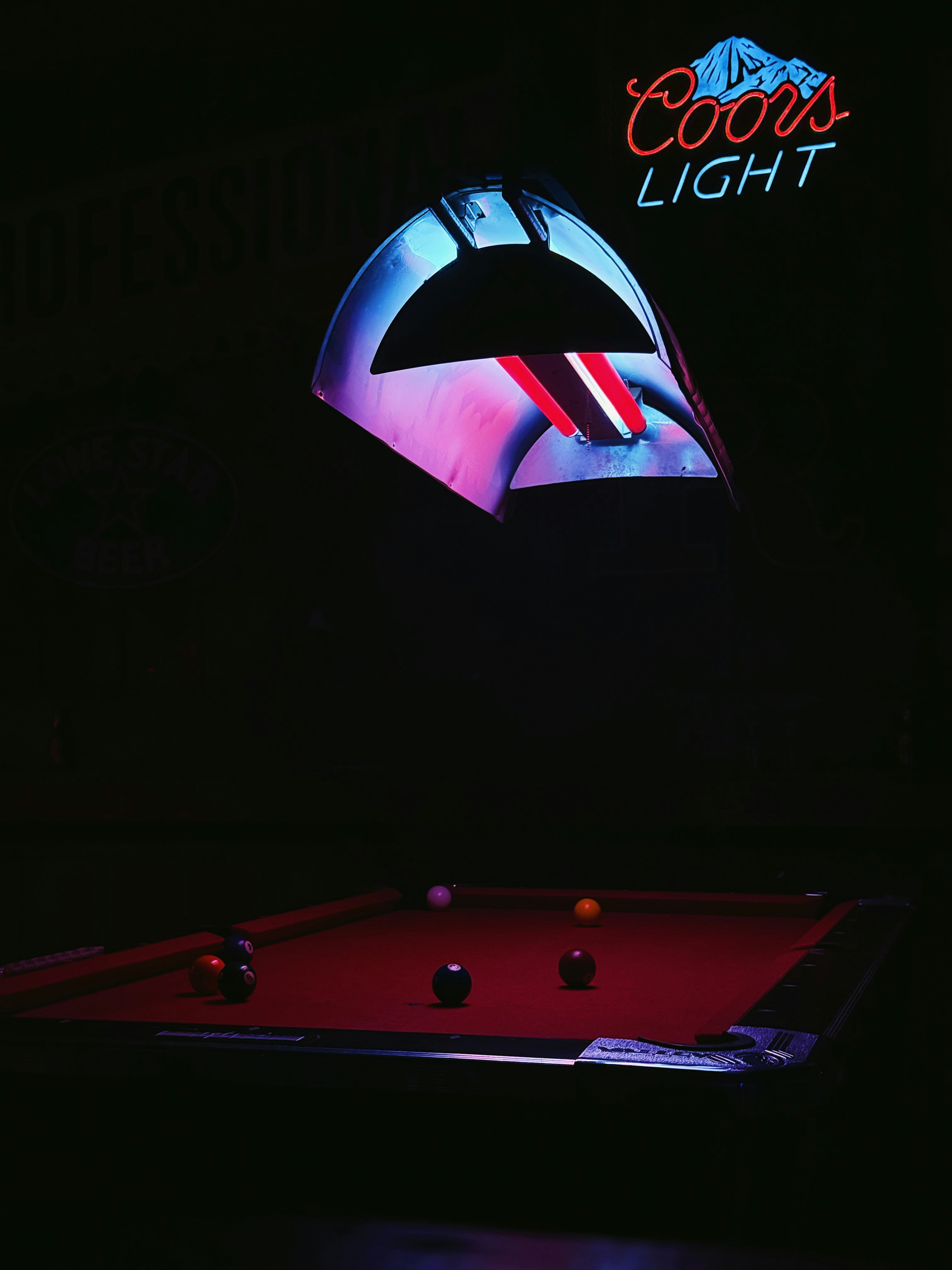 Tavolo da biliardo con insegna luminosa coors in camera oscura