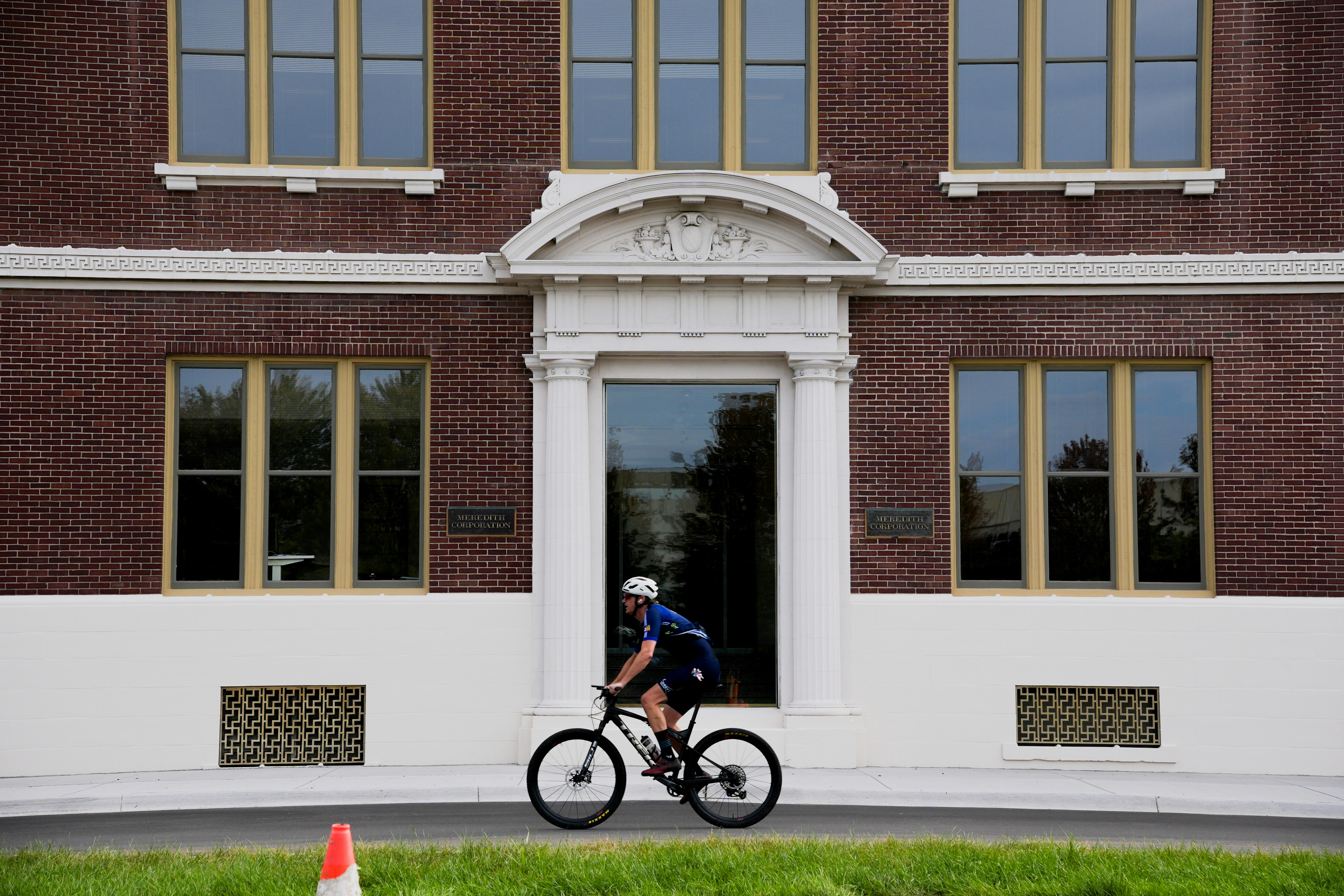 Cyclist rides past brick building with large windows