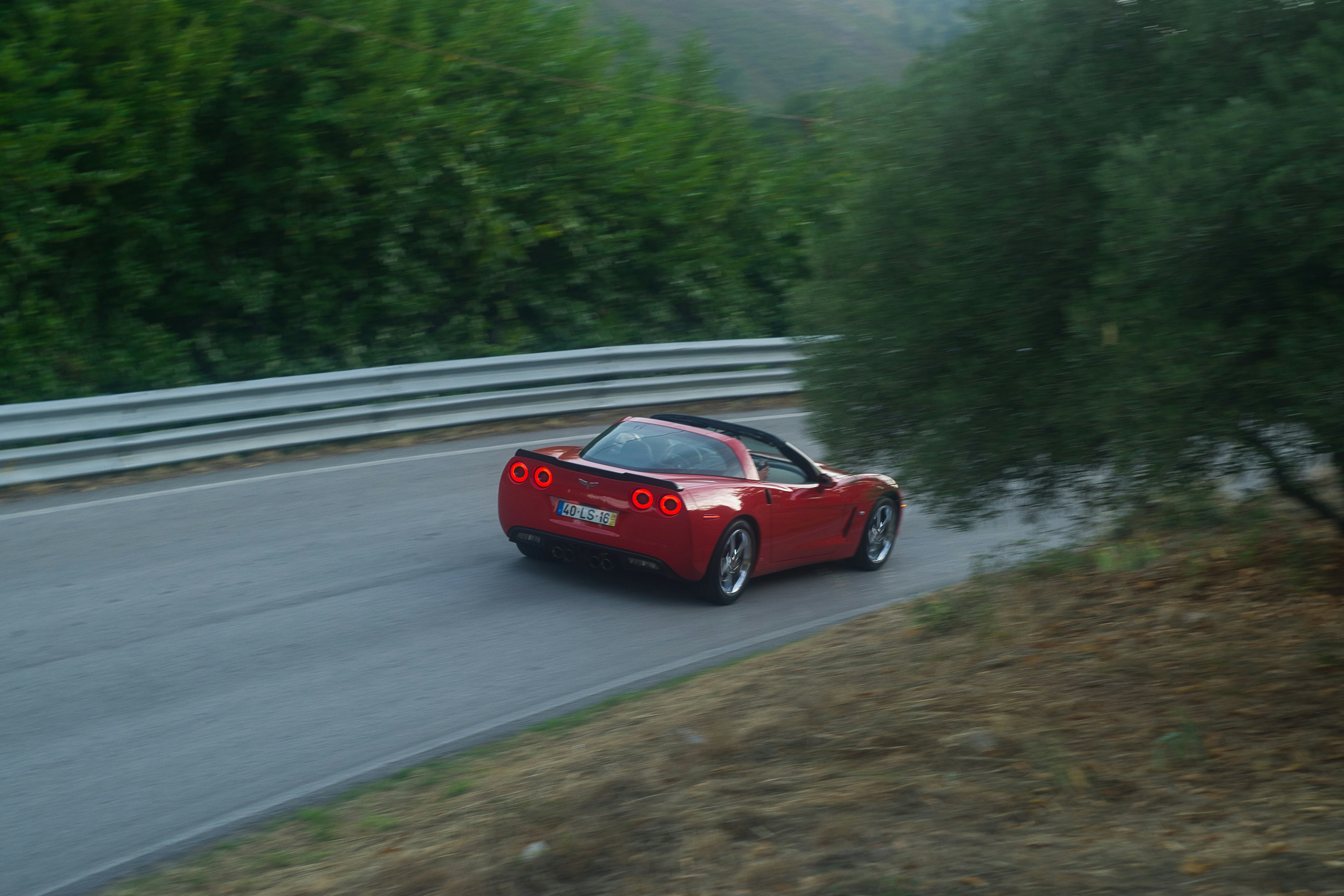 Red sports car driving on a winding road.