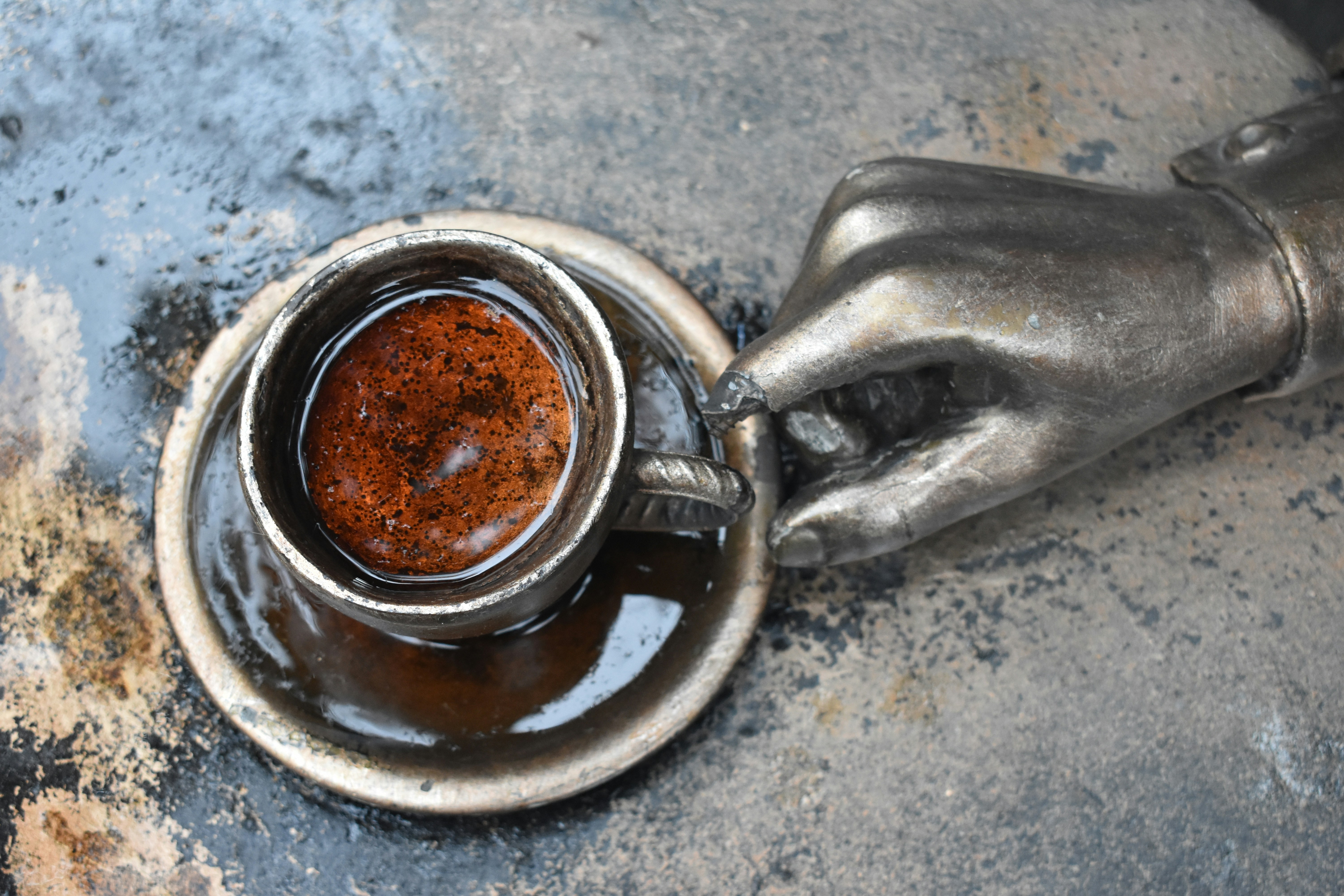 A metallic hand holds a cup of coffee.