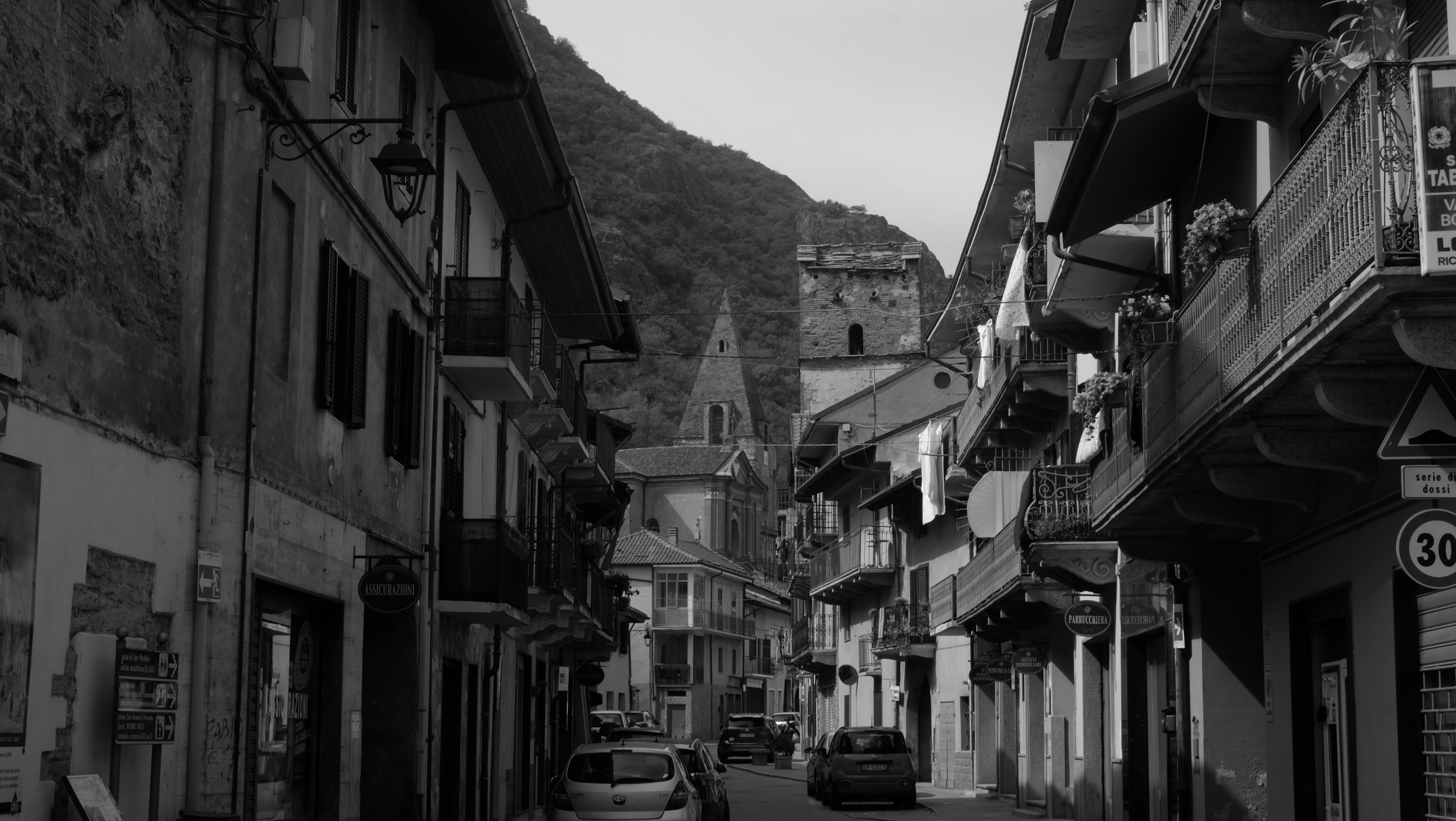 Black and white street view with buildings and mountain.