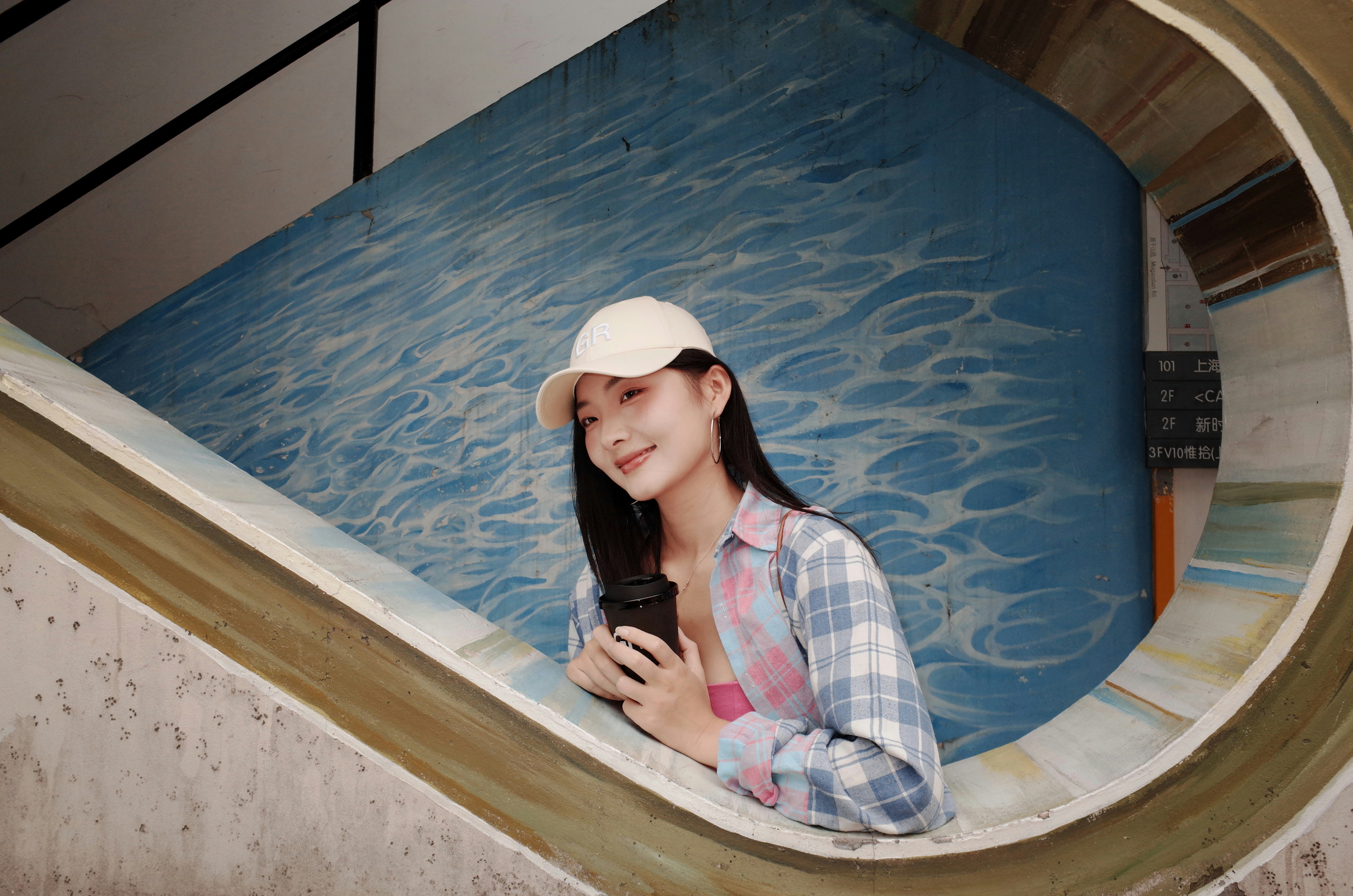 Young woman in baseball cap and plaid shirt smiles