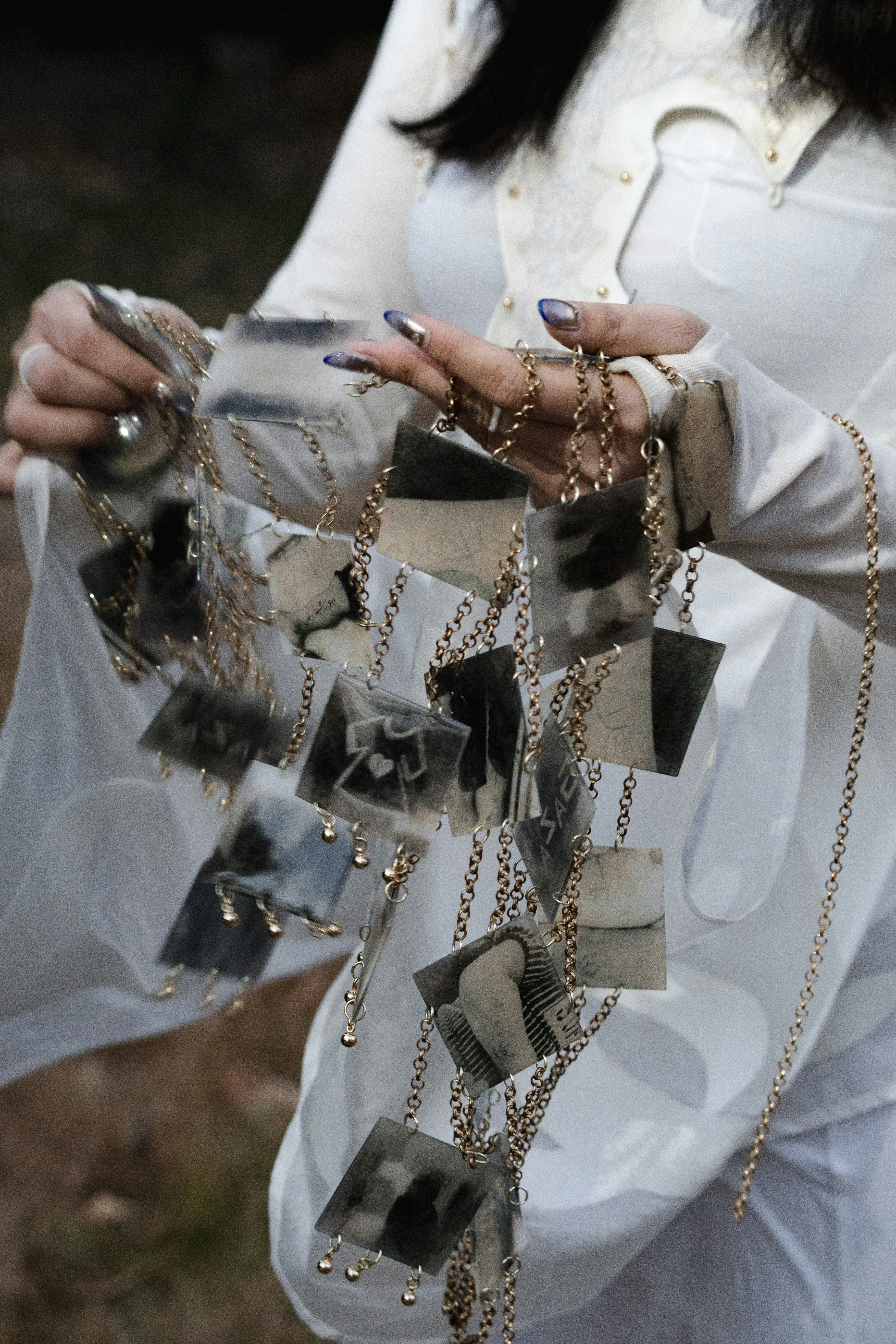 Woman holding a necklace with small black and white photos.