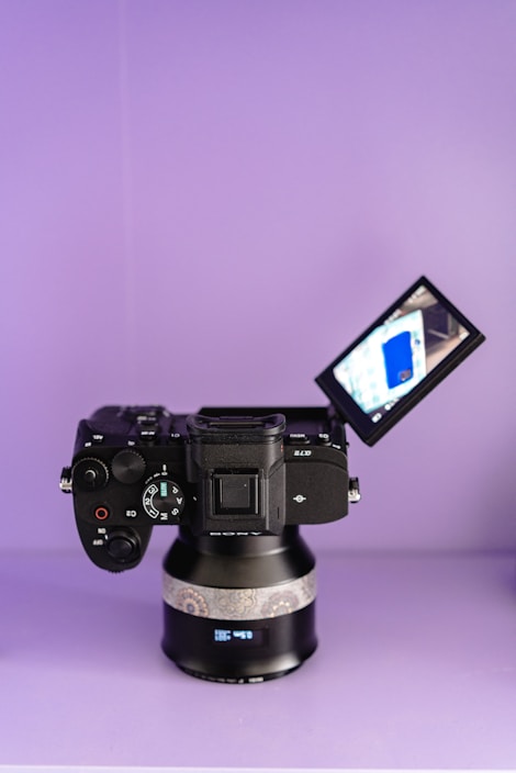 Digital camera with flipped screen on purple background