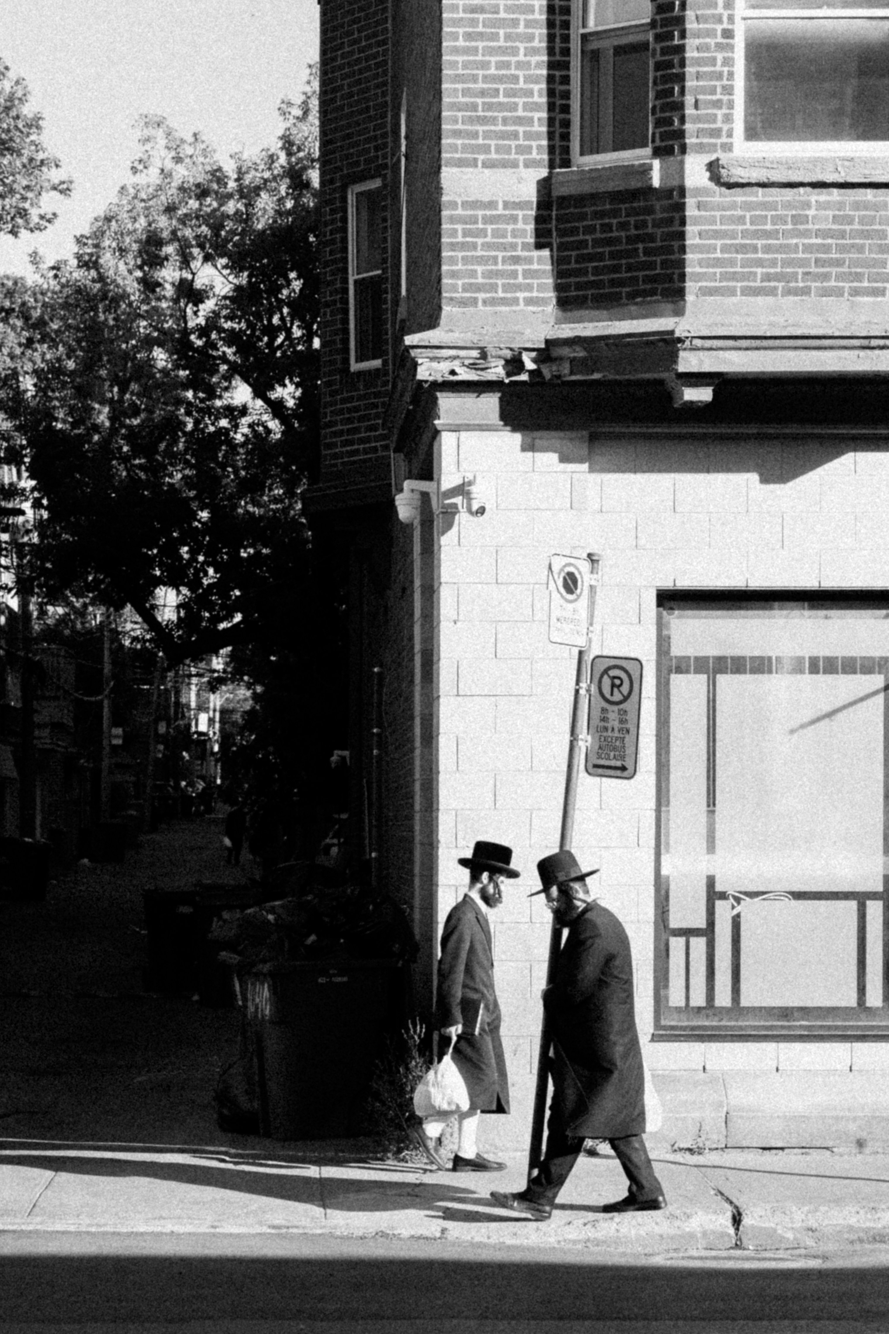 Two men in hats walk on a sidewalk.