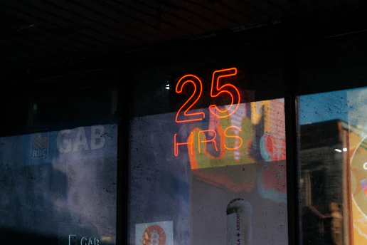 Neon sign with "25 hrs" reflects on glass