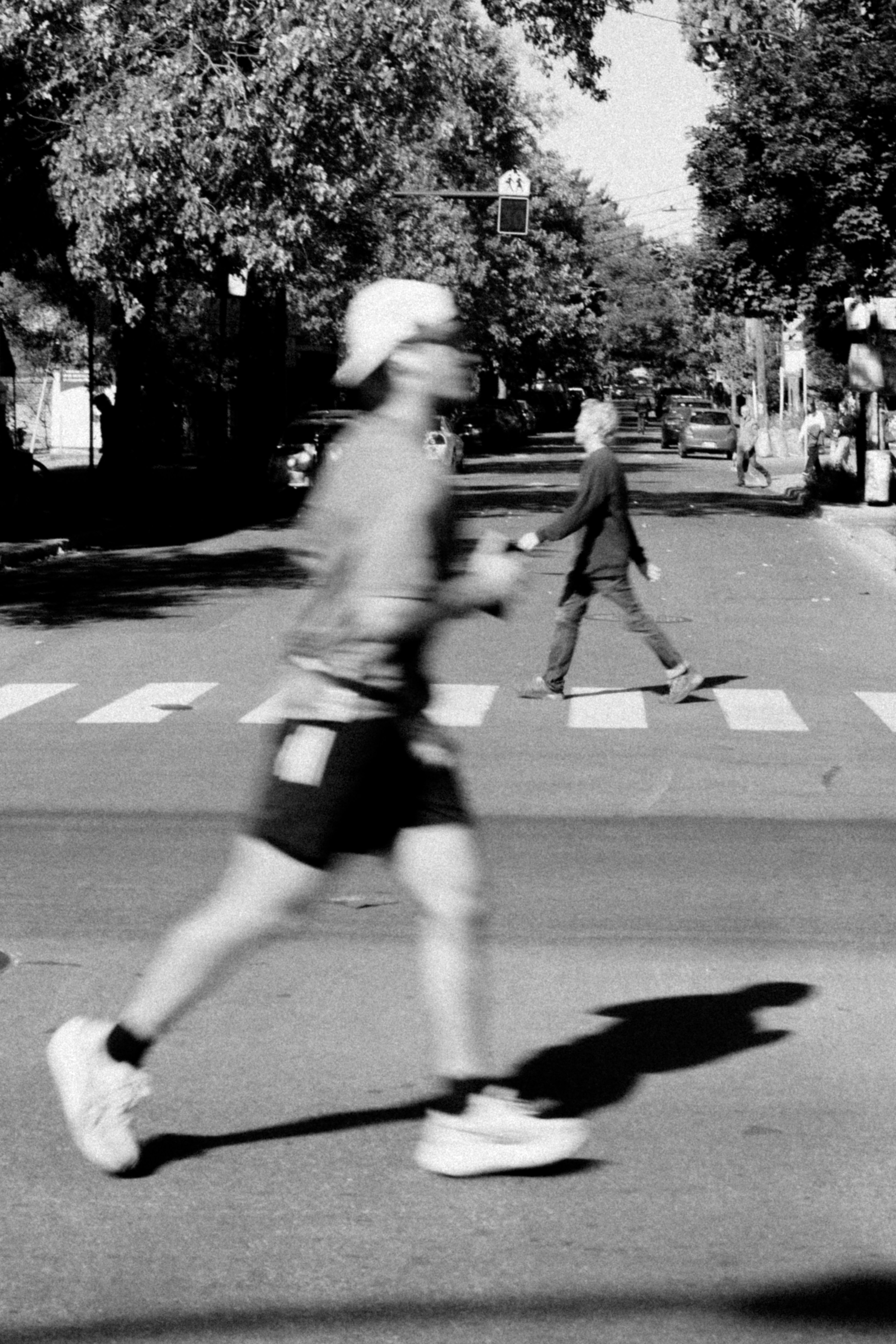 Runner crosses street with pedestrian in background