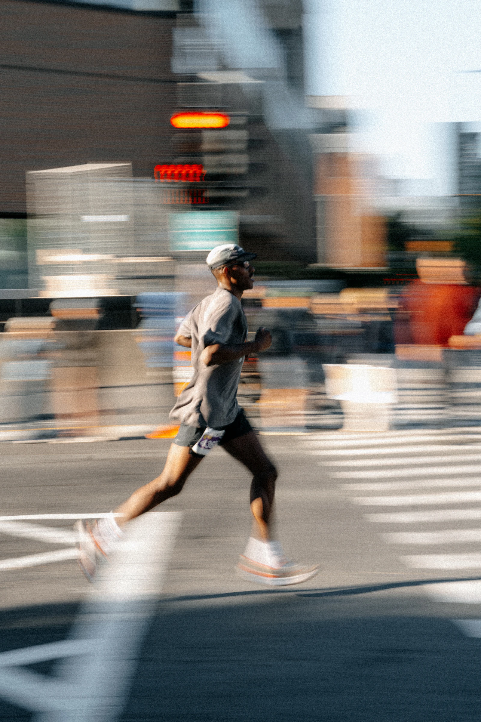 A man running across a city street, the background blurred with speed