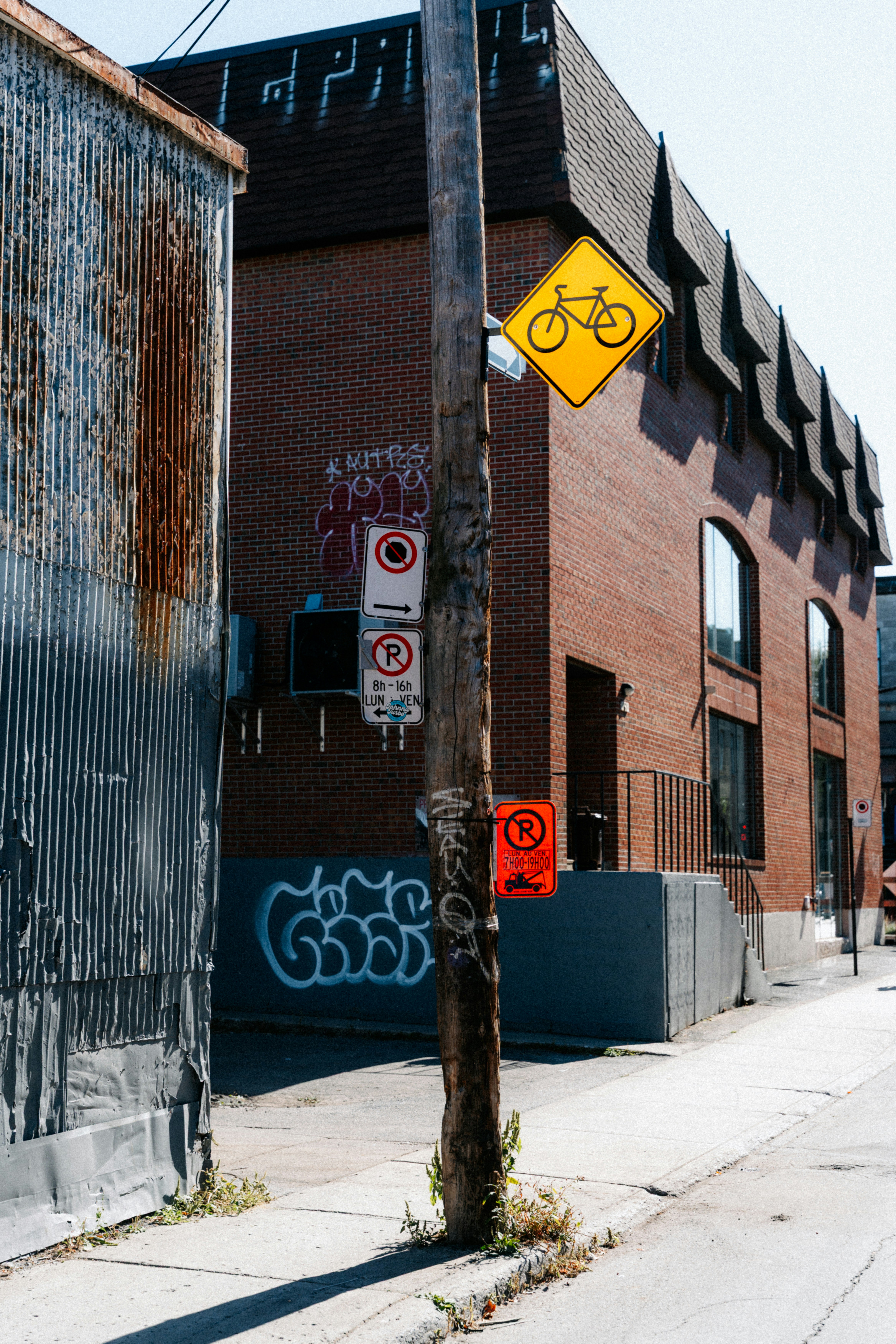 Street with brick building, graffiti, and bicycle sign.