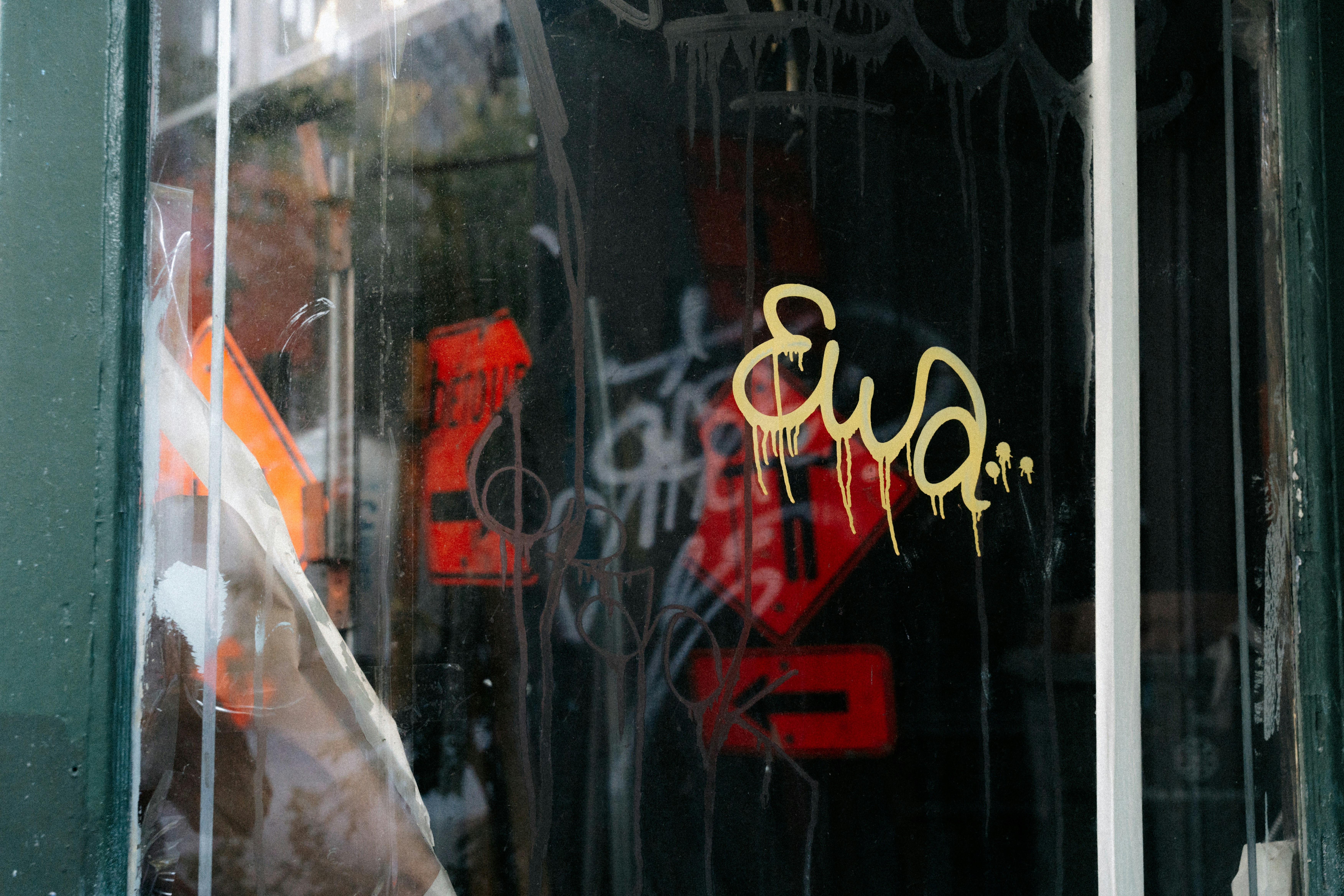 Graffiti on a reflective window with a person visible.