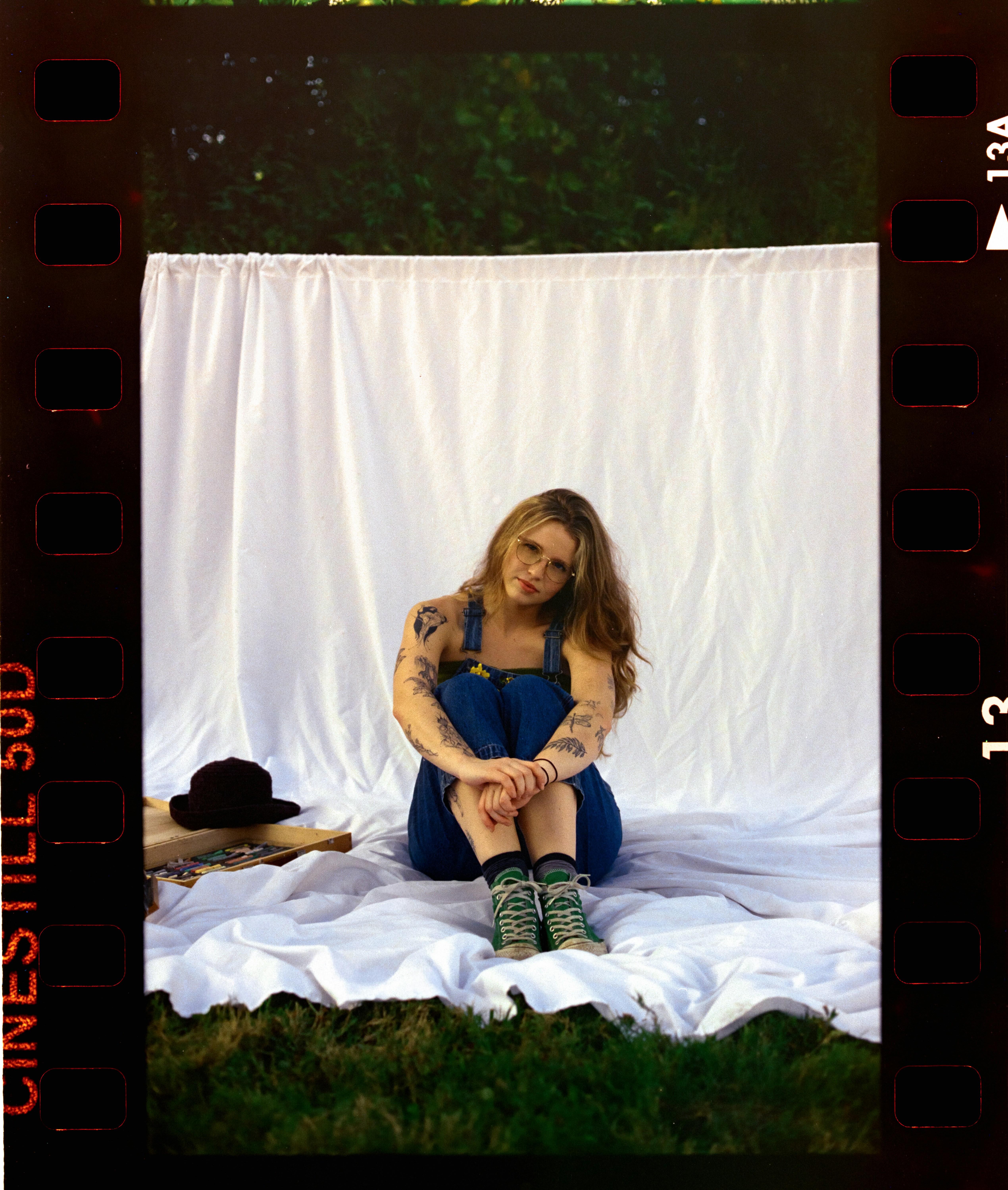 Woman in overalls sitting on white sheet outdoors
