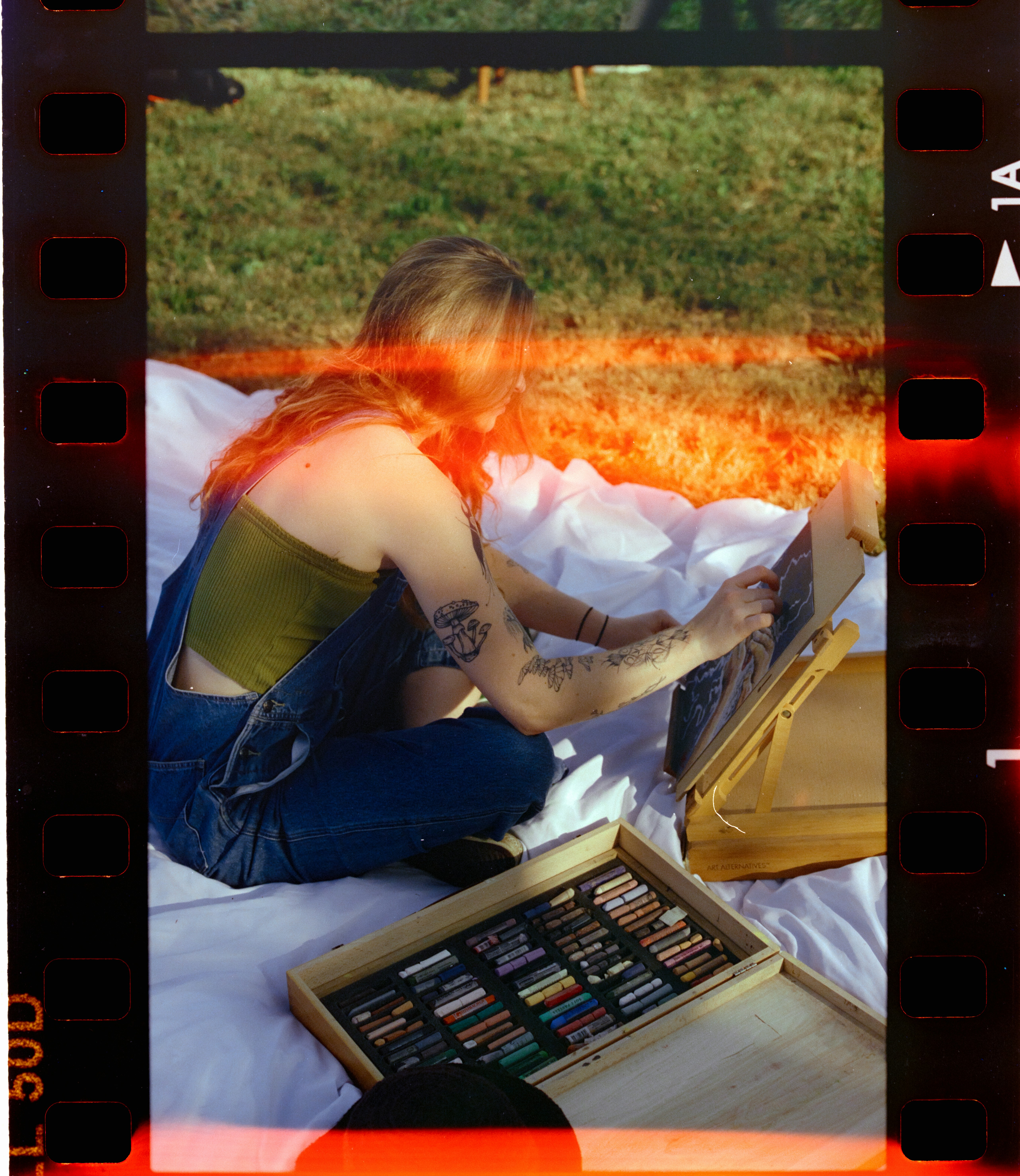Woman drawing with pastels on a blanket outdoors