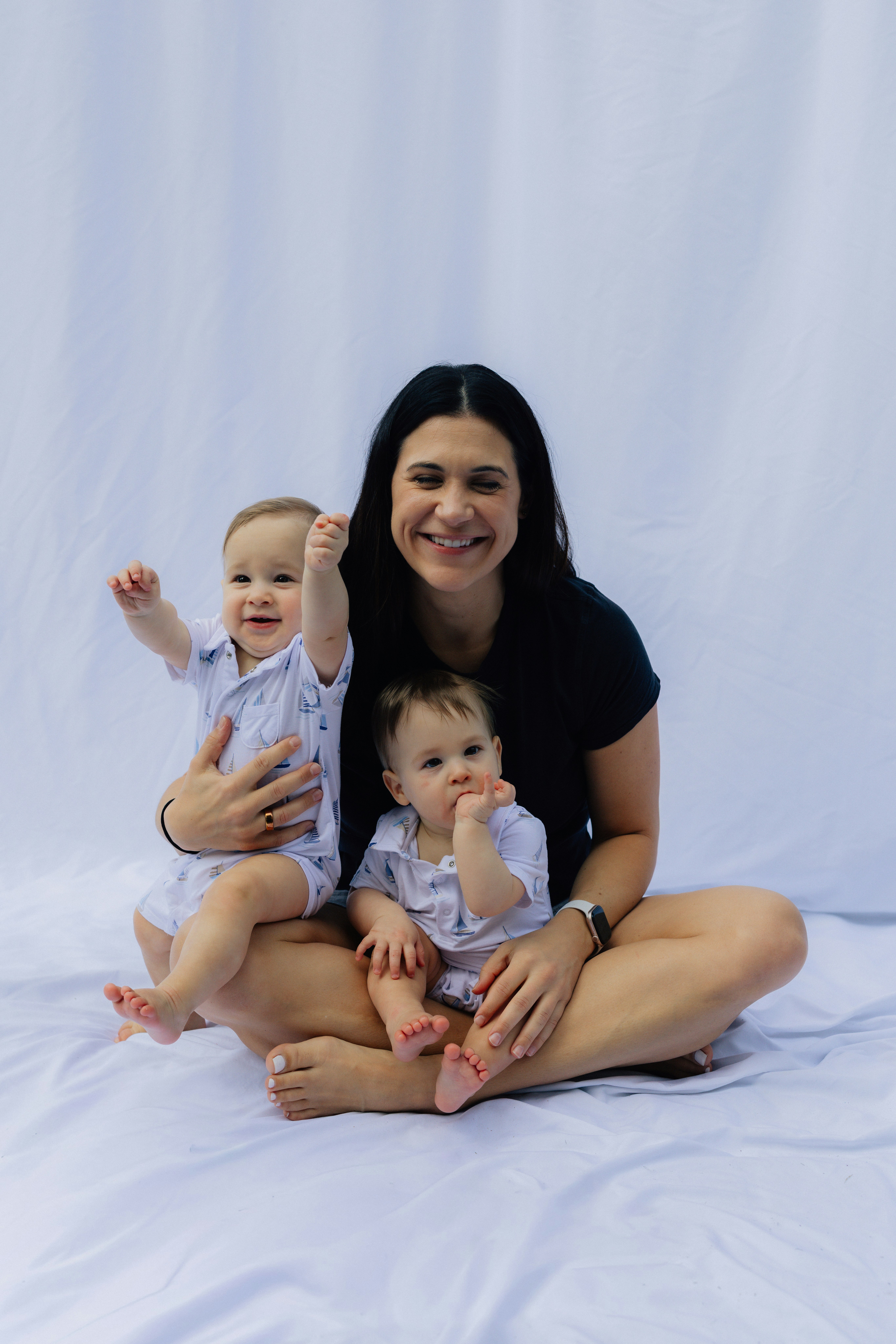 Ibu dengan dua bayi duduk di latar belakang putih