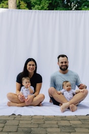 Family with two babies sitting on white backdrop