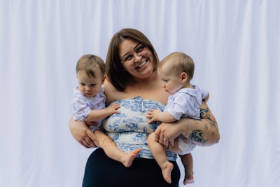 Woman holding two babies in front of white backdrop