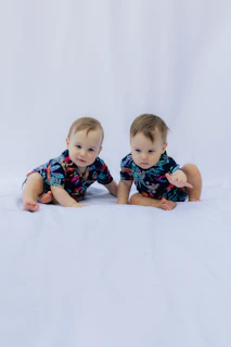 Two babies in matching floral shirts on white background