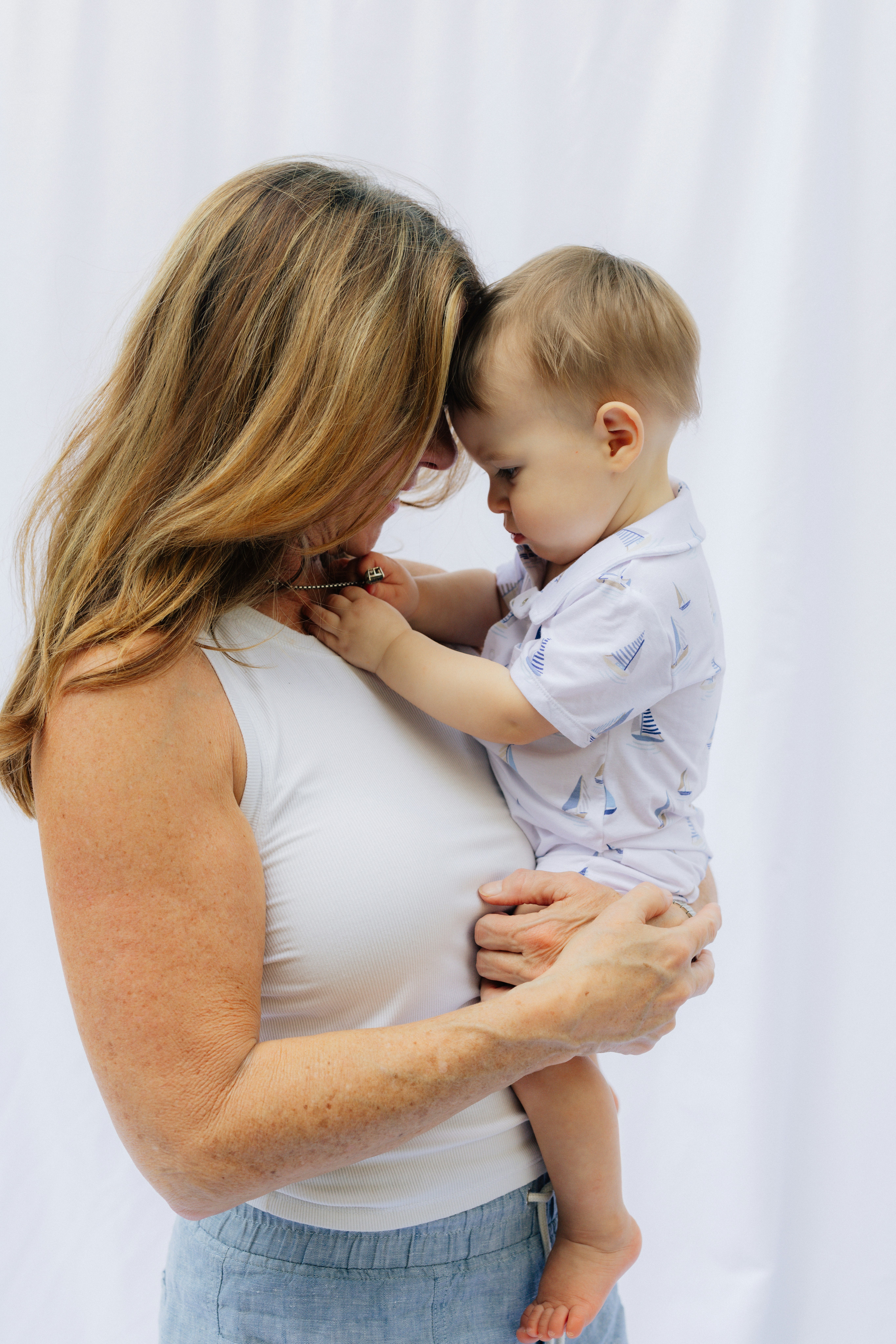 Woman holding a baby against a white background.