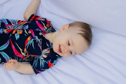 A smiling baby in a colorful tropical shirt