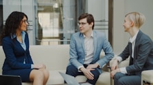 Three business people talking on a sofa.
