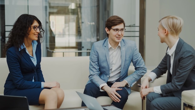 Three business people in a meeting on a couch.