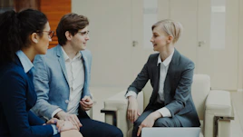 Three professionals in business attire conversing indoors.