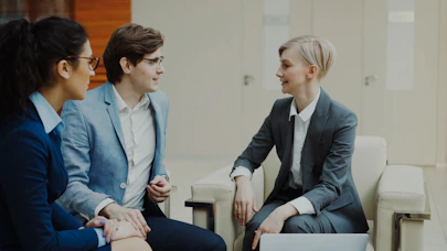 Three professionals in business attire conversing indoors.