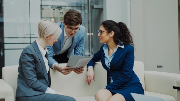 Three business people in suits discussing documents.