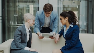 Three business people looking at tablet on sofa