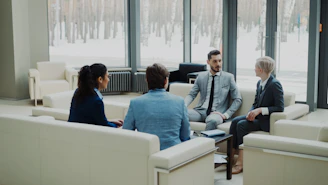 Four professionals in a modern office meeting space.