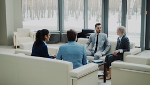 Four professionals in a modern office meeting space.
