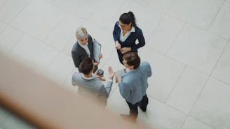 Four business people talking in a modern office lobby.