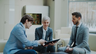Three professionals discussing a tablet in a modern office.