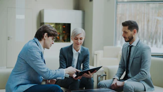 Three professionals discussing a tablet in a modern office.
