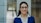 A smiling woman wearing glasses and a blue suit.