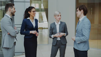 Four business professionals conversing in a modern office lobby.