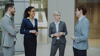 Four business professionals conversing in a modern office lobby