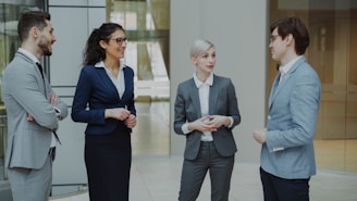 Four business professionals conversing in a modern office lobby.