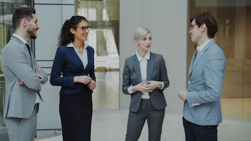 Four business professionals conversing in a modern office lobby.