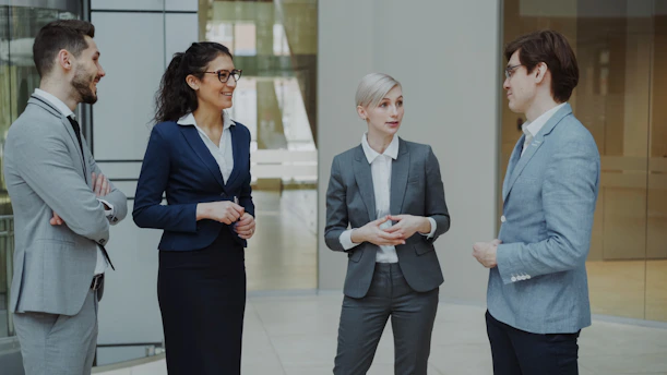 Four business professionals conversing in a modern office lobby