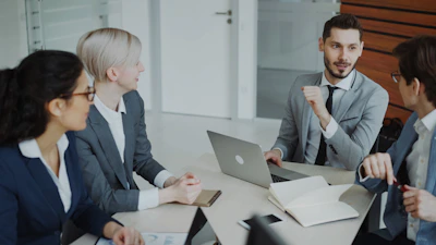 Four professionals in a business meeting around a table.