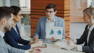 Man presenting charts to colleagues in a meeting.