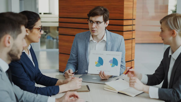 Man presenting charts to colleagues in a meeting.