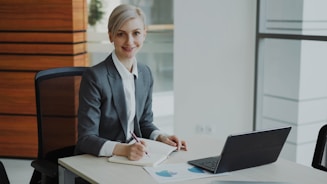 A professional woman in a suit works at a desk.